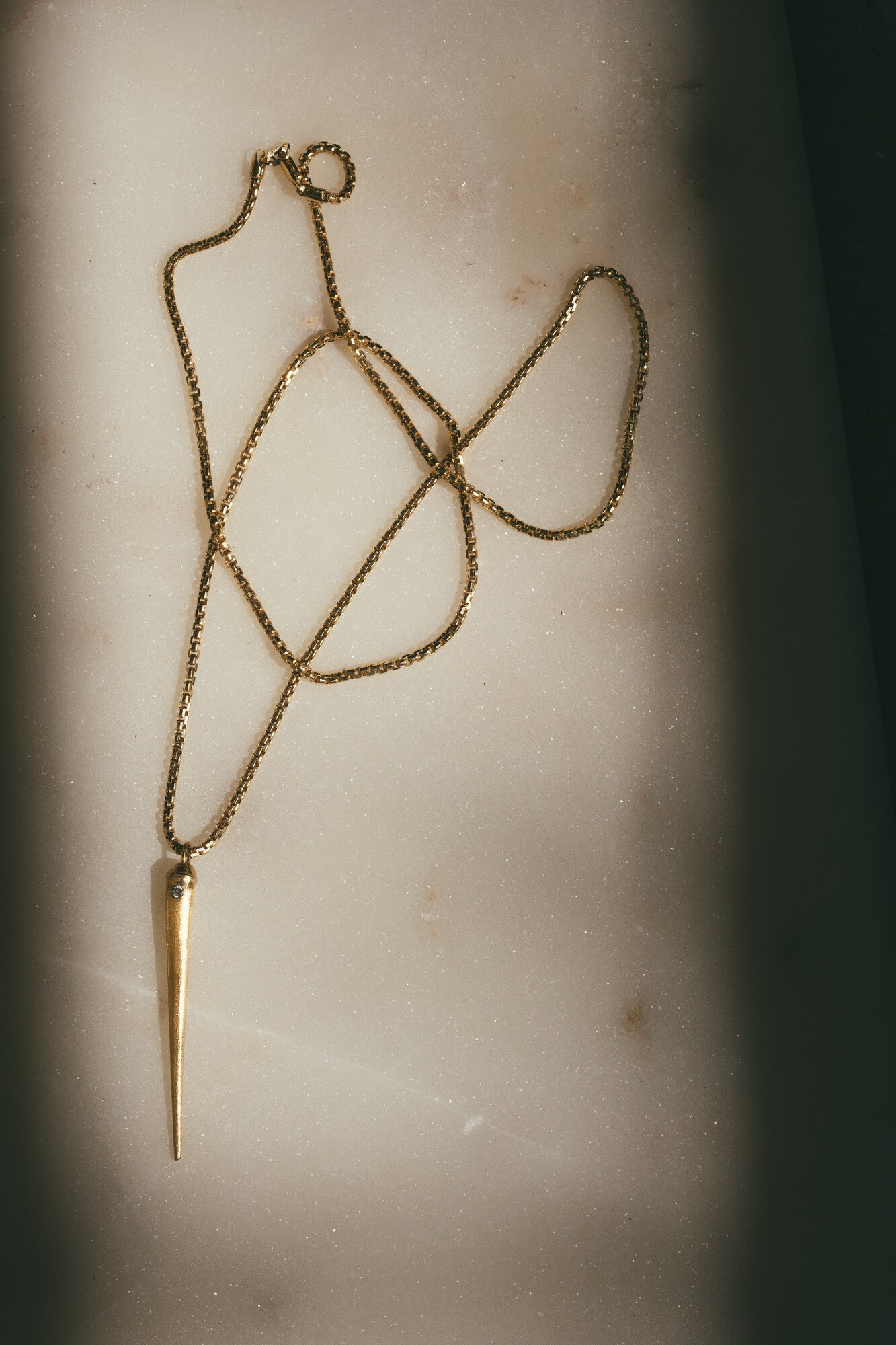 THE GOLD SEA URCHIN SPIKE CHARM WITH DIAMOND WITH SHADOWS ON BOTH SIDES OF THE IMAGE