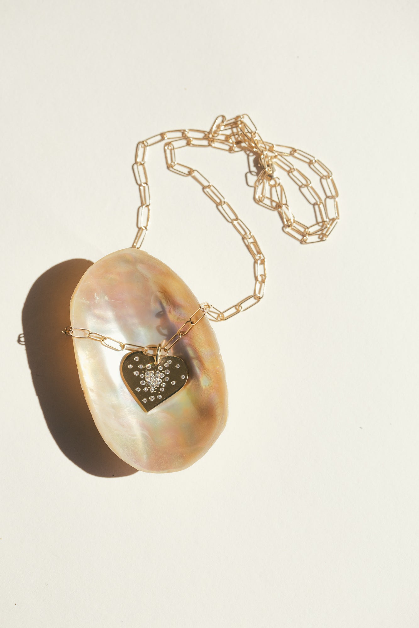 THE GOLD HEART DIAMOND BURST CHARM ON A SEA SHELL