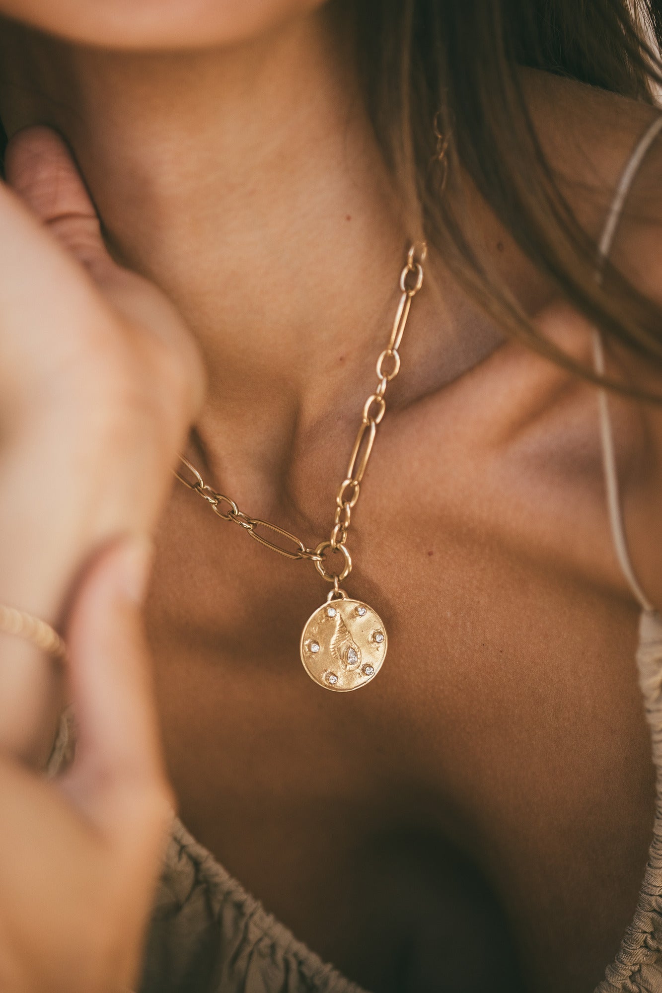 A CLOSE UP OF THE LARGE GOLD HORN SHELL CHARM WITH DIAMONDS AROUND THE MODELS NECK