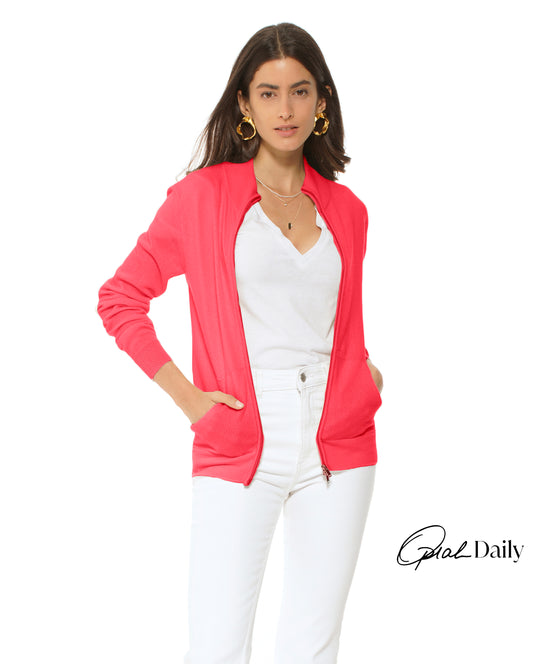 Woman wearing a pink cardigan over a white top and pants on a white background
