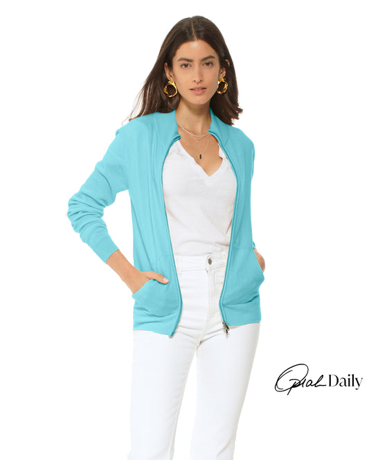 Woman wearing a light blue cardigan over a white top and pants on a white background