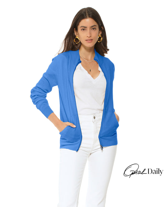 Woman wearing a blue cardigan over a white top and pants on a white background