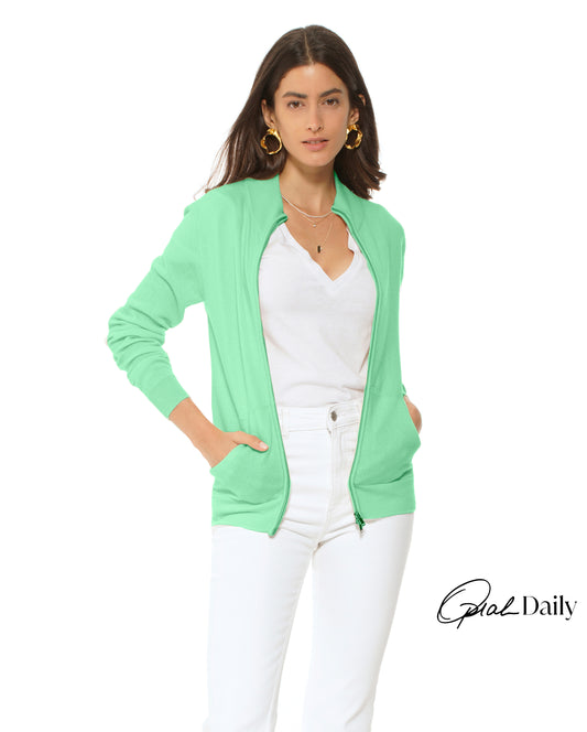 Woman wearing a light green cardigan over a white top and pants on a white background