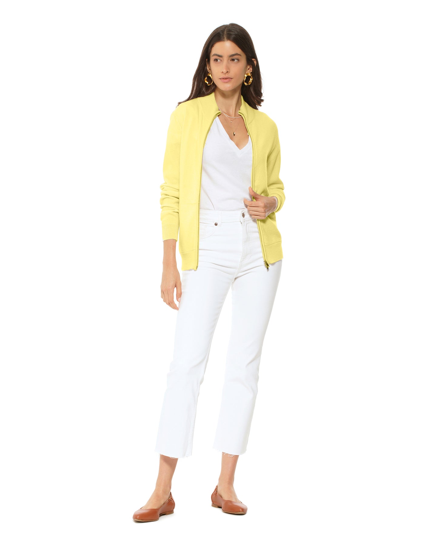 Woman wearing a yellow cardigan over a white top and pants on a white background
