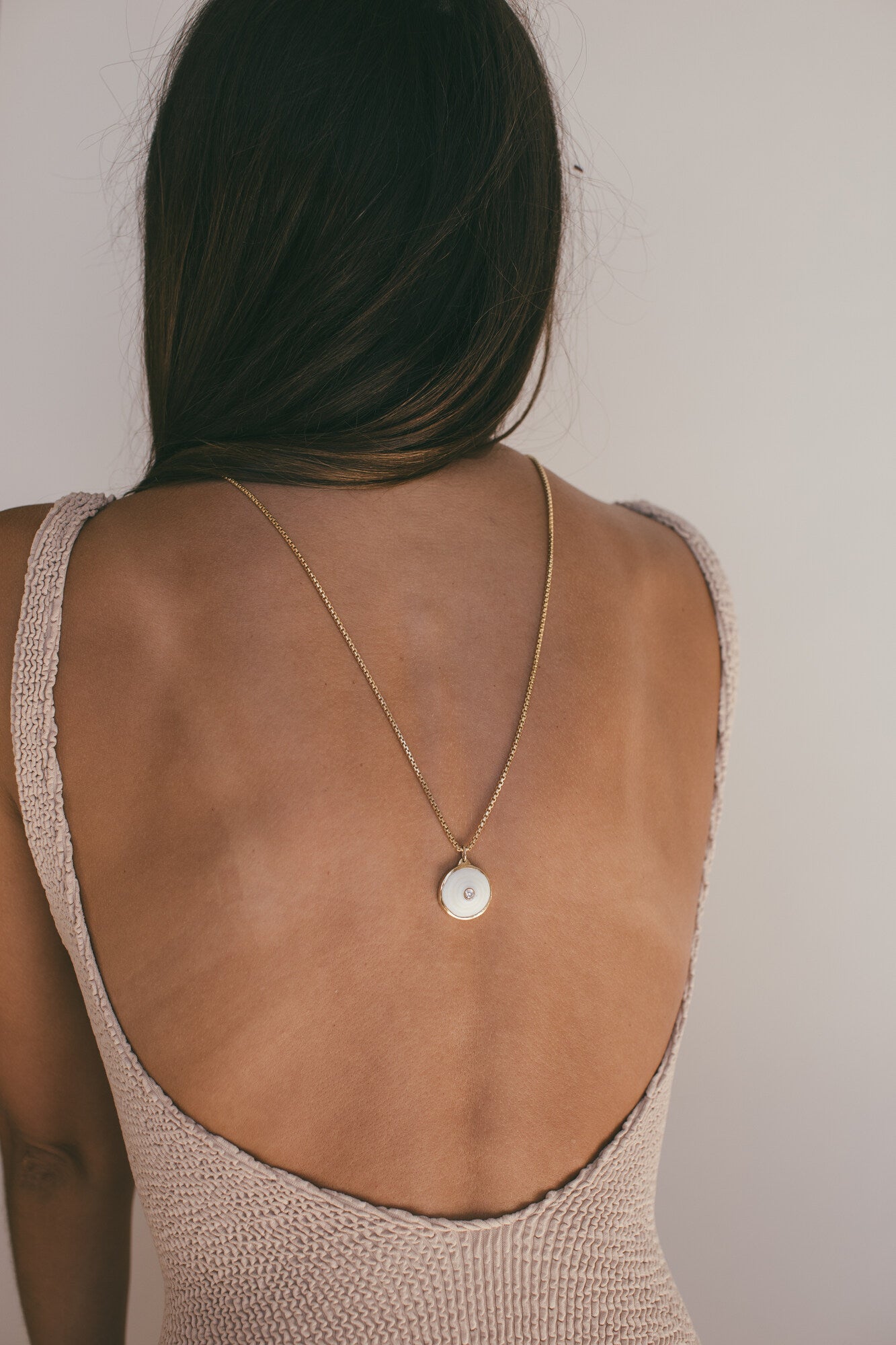 THEMEDIUM 18K GOLD PUKA CHARM WITH DIAMOND-ONE-OF-A-KIND-WHITE AROUND A MODELS NECK