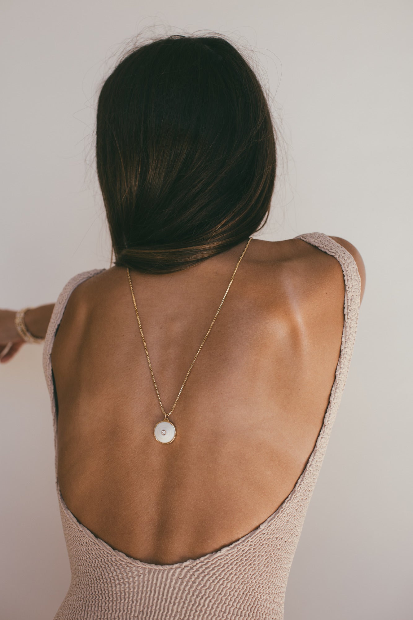 MEDIUM 18K GOLD PUKA CHARM WITH DIAMOND-ONE-OF-A-KIND-WHITE ON A MODELS BACK