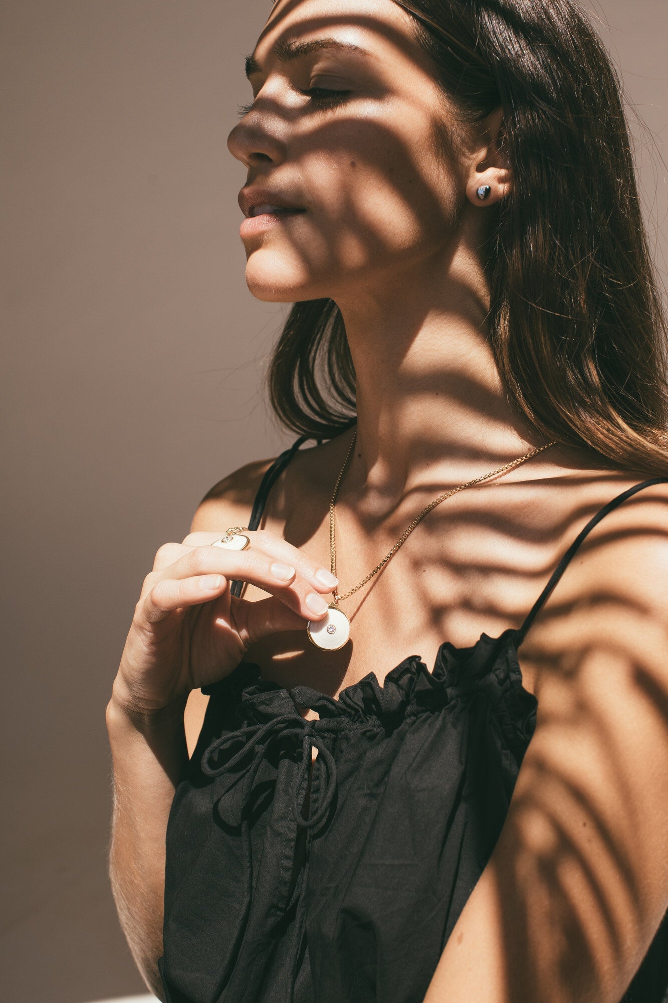 A MODEL HOLDING THE MEDIUM 18K GOLD PUKA CHARM WITH DIAMOND-ONE-OF-A-KIND-WHITE