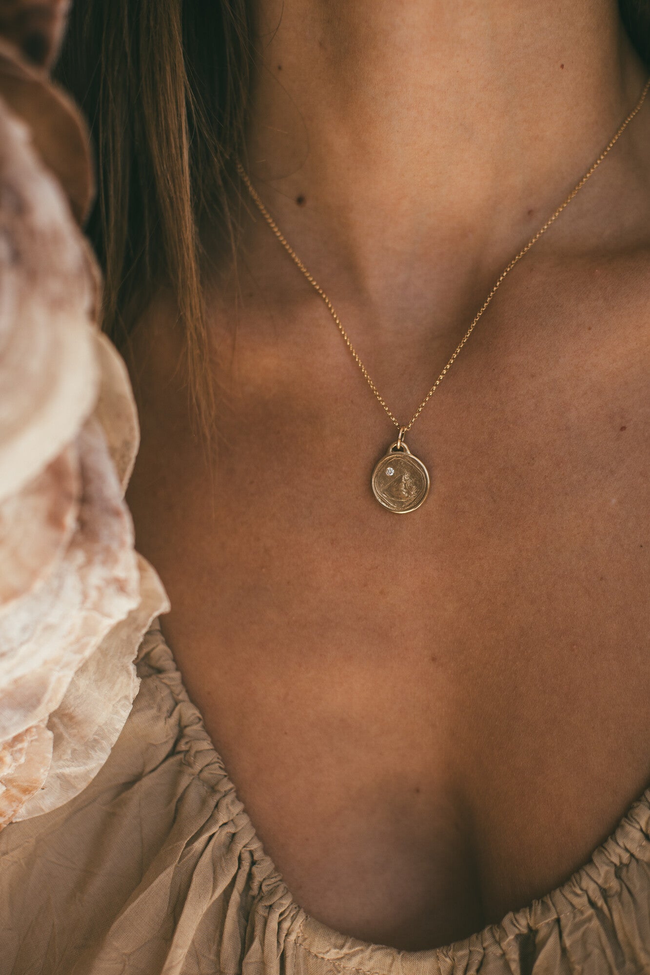 A CLOSE UP IMAGE OF SMALL GOLD CONCH SHELL CHARM WITH DIAMOND