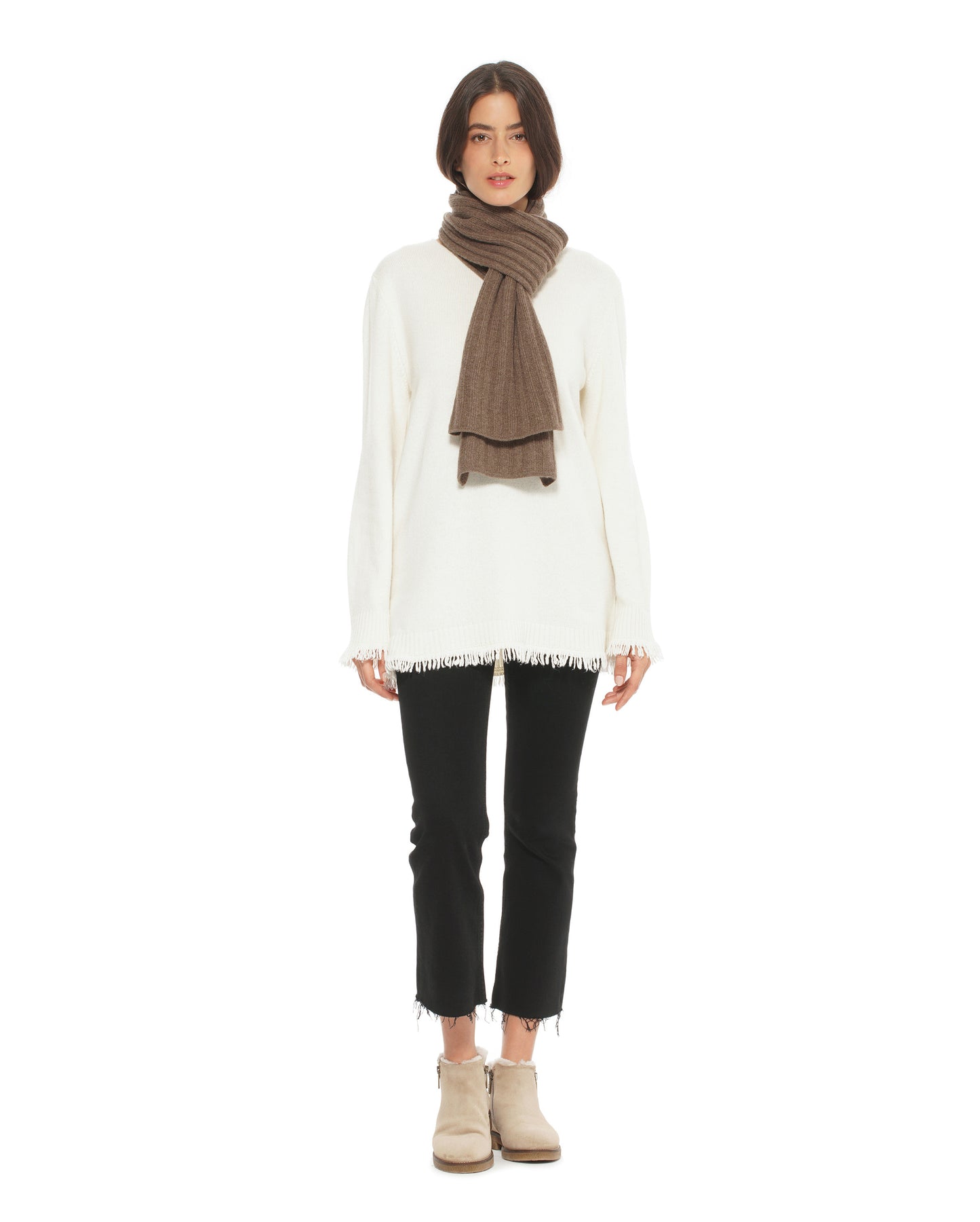 Person wearing a white sweater, black pants, and a brown scarf on a white background
