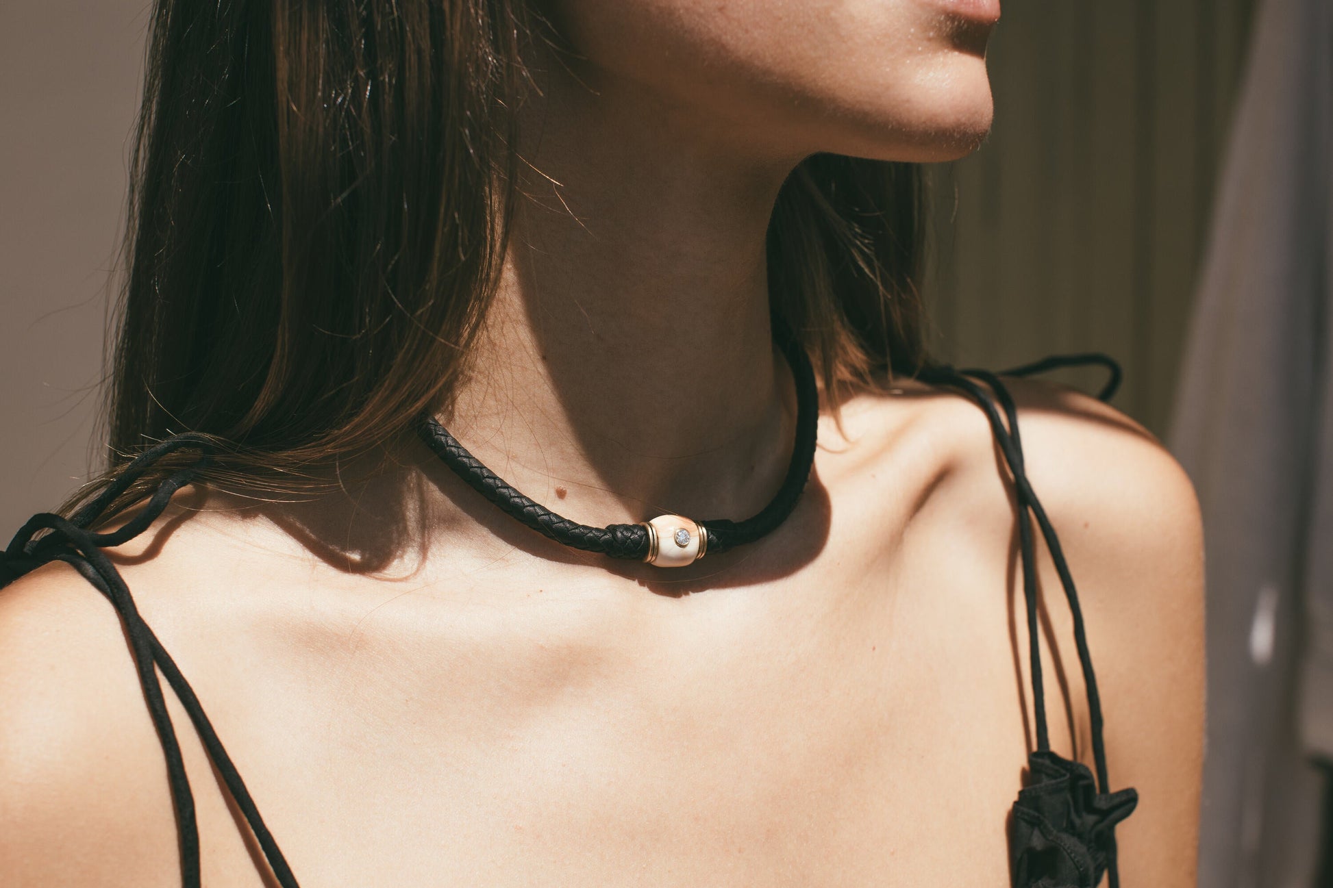 A CLOSE PHOTO OF THE 14K GOLD CONCH CHARM WITH DIAMOND LEATHER CHOKER AROUND A MODELS NECK