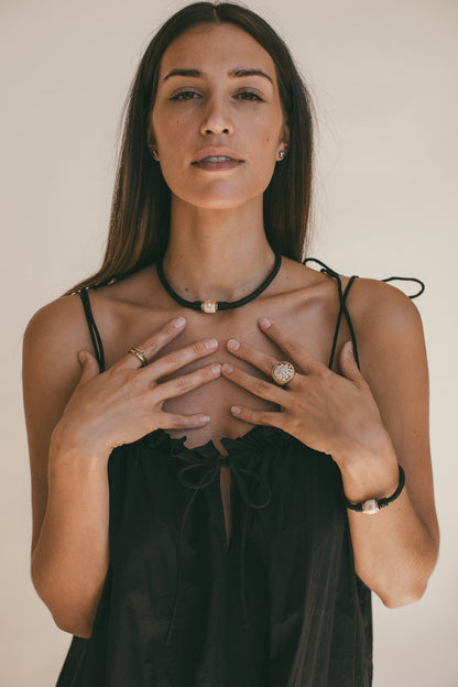 A PORTRAIT PHOTO OF A MODEL WEARING THE 14K GOLD CONCH CHARM WITH DIAMOND LEATHER CHOKER