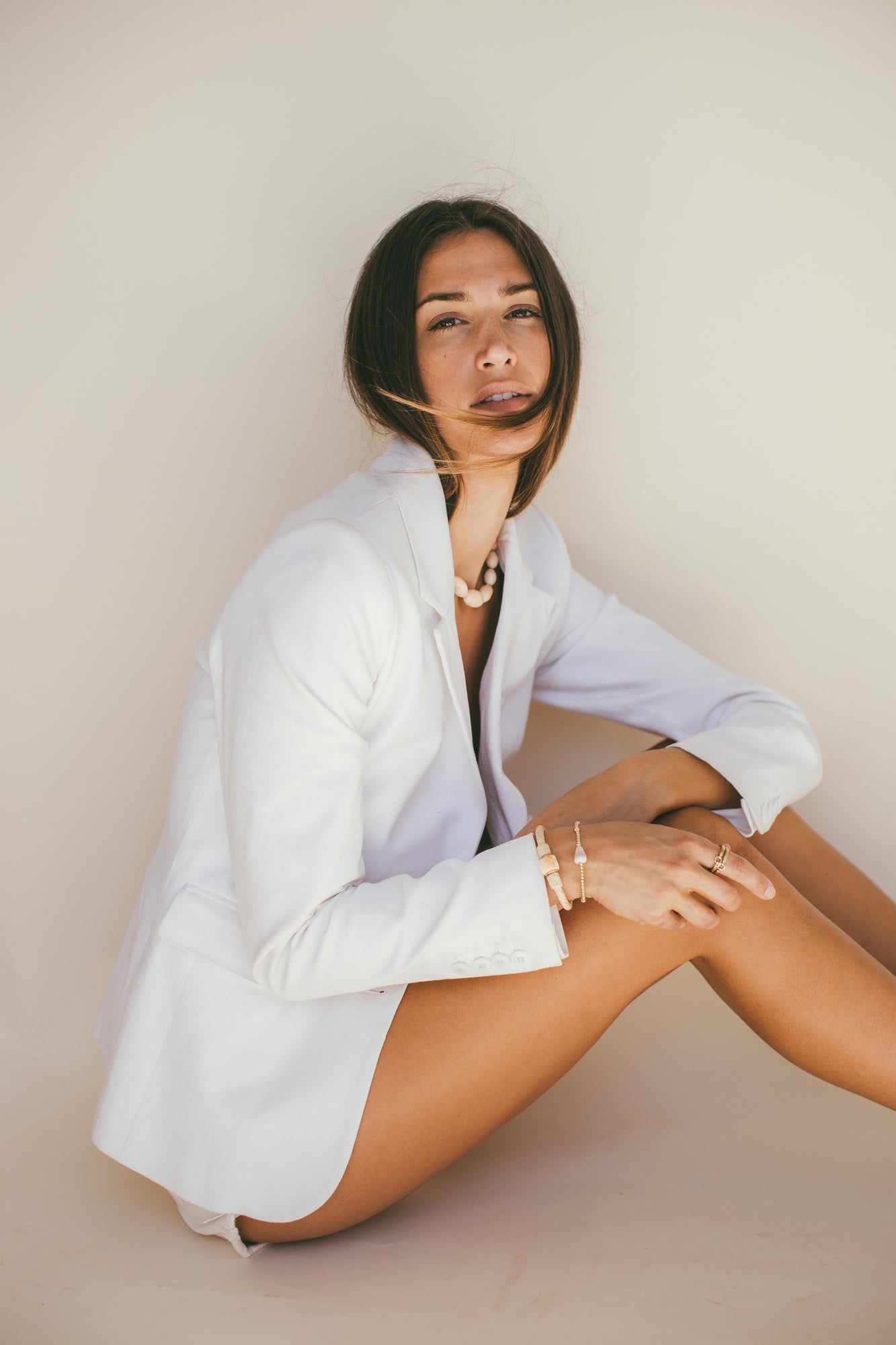 A MODEL WITH A WHITE JACKET WEARING THE 14K GOLD VINTAGE CONCH WITH DIAMOND LEATHER BRACELET