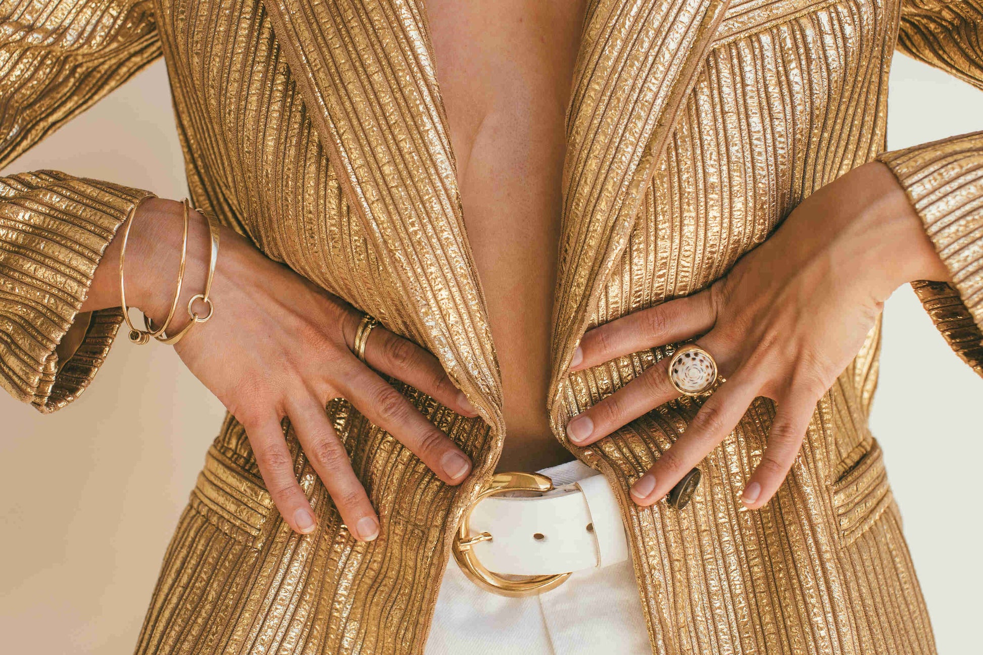 A MODEL WEARING A GOLD BLAZZER WITH THE 18K GOLD PUKA RING-ONE-OF-A-KIND-PATTERN ON HER LEFT HAND 