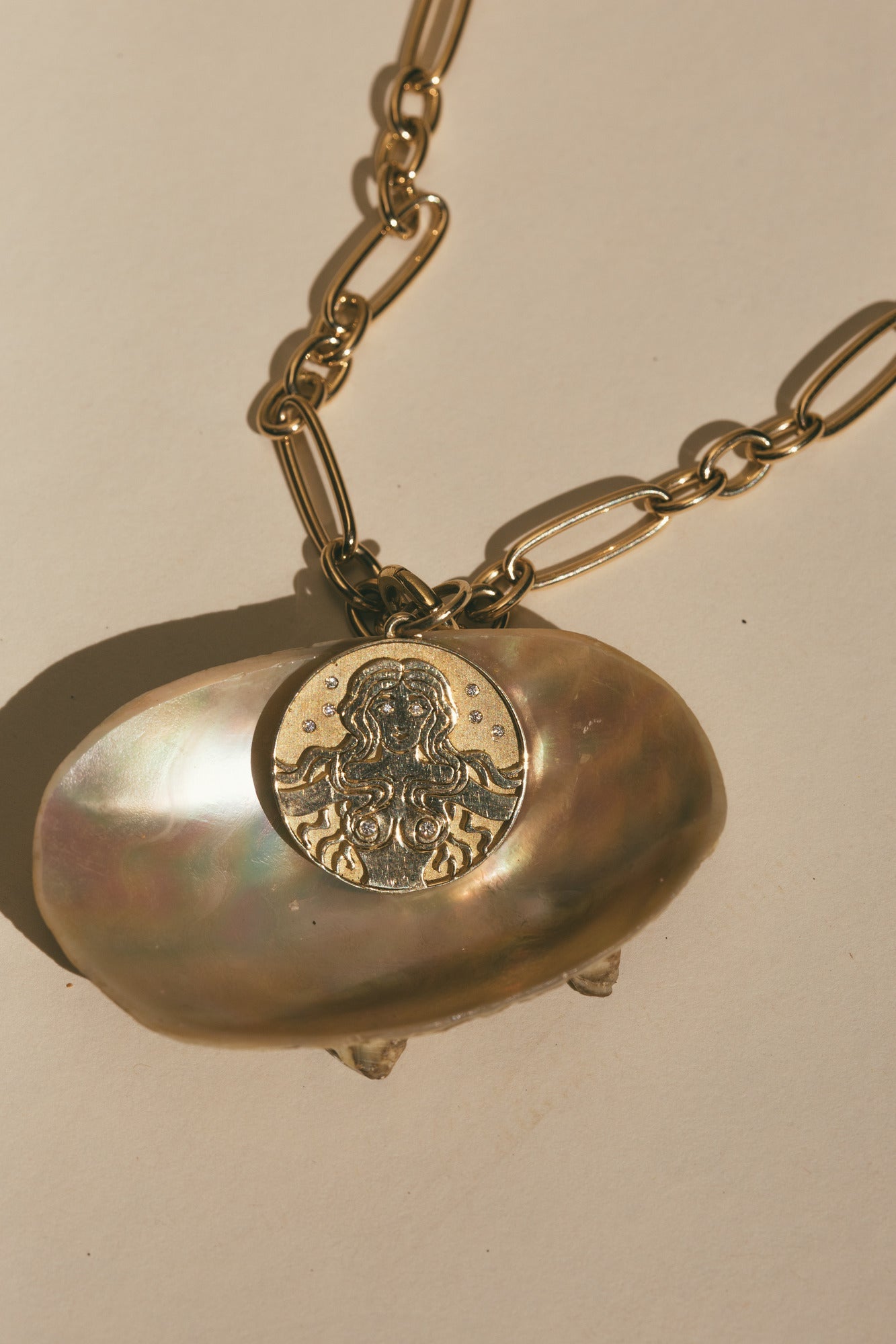 THE GOLD MERMAID DIAMOND CHARM ON TOP OF A BROWN SEA SHELL 