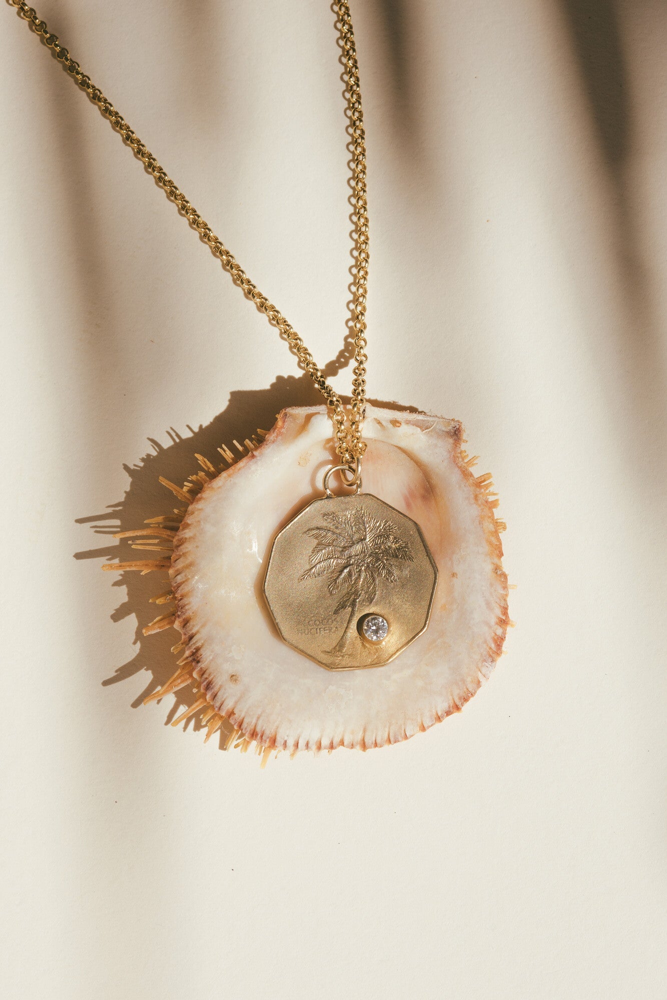 THE GOLD PALM TREE & DIAMOND COCONUT CHARM ON TOP OF A SEA SHELL