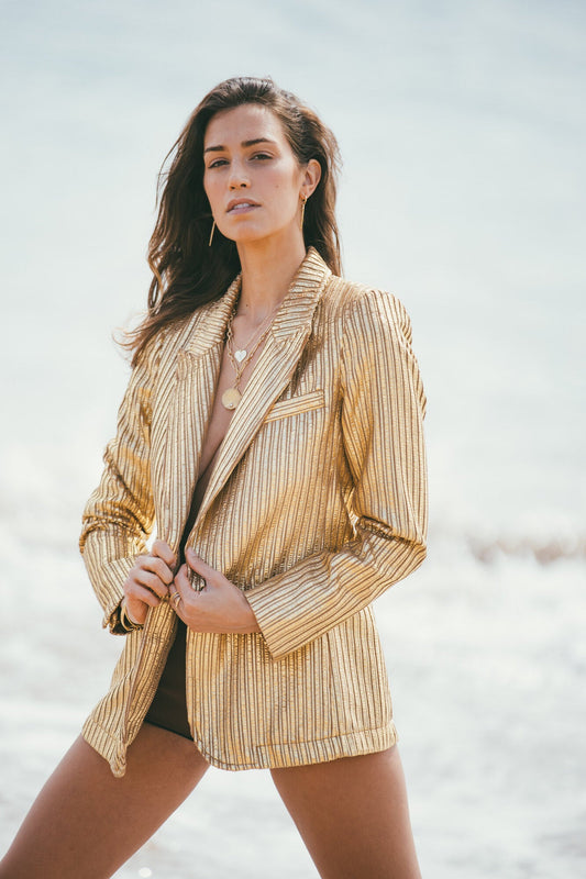 A MODEL WITHA GOLD JACKET WEARING THE GOLD PALM TREE & DIAMOND COCONUT CHARM
