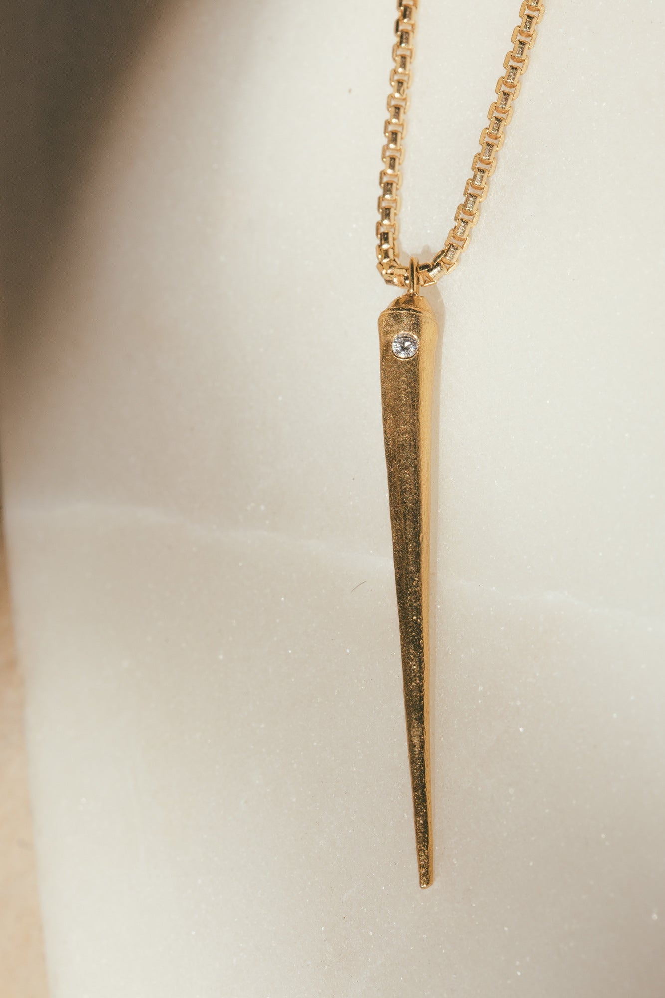 A CLOSE UP GOLD SEA URCHIN SPIKE CHARM WITH DIAMOND