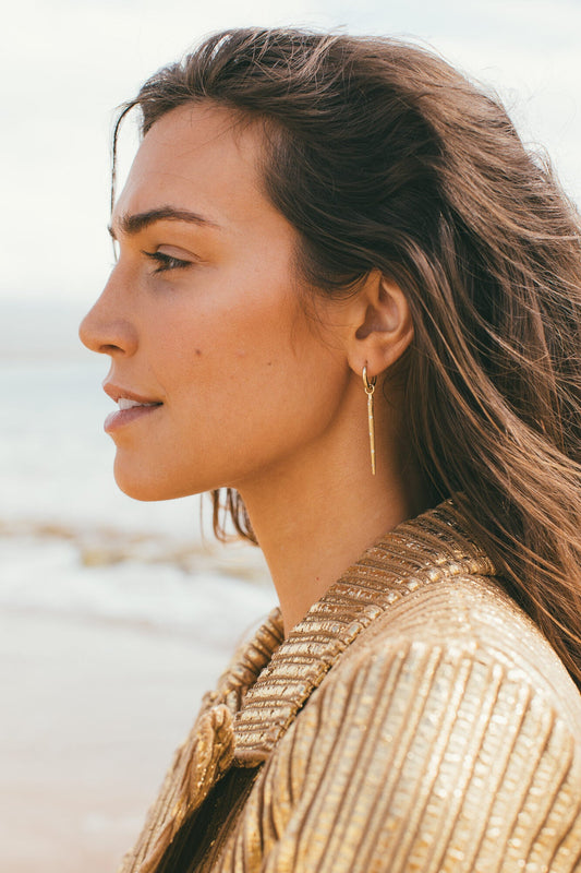 Model looking to the side with gold sea urchin earrings