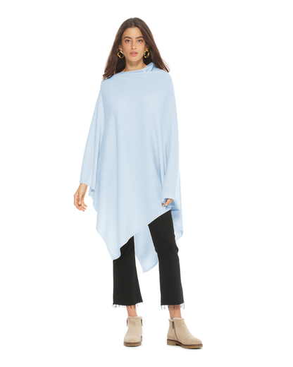 Woman wearing a light blue poncho over a black outfit on a white background
