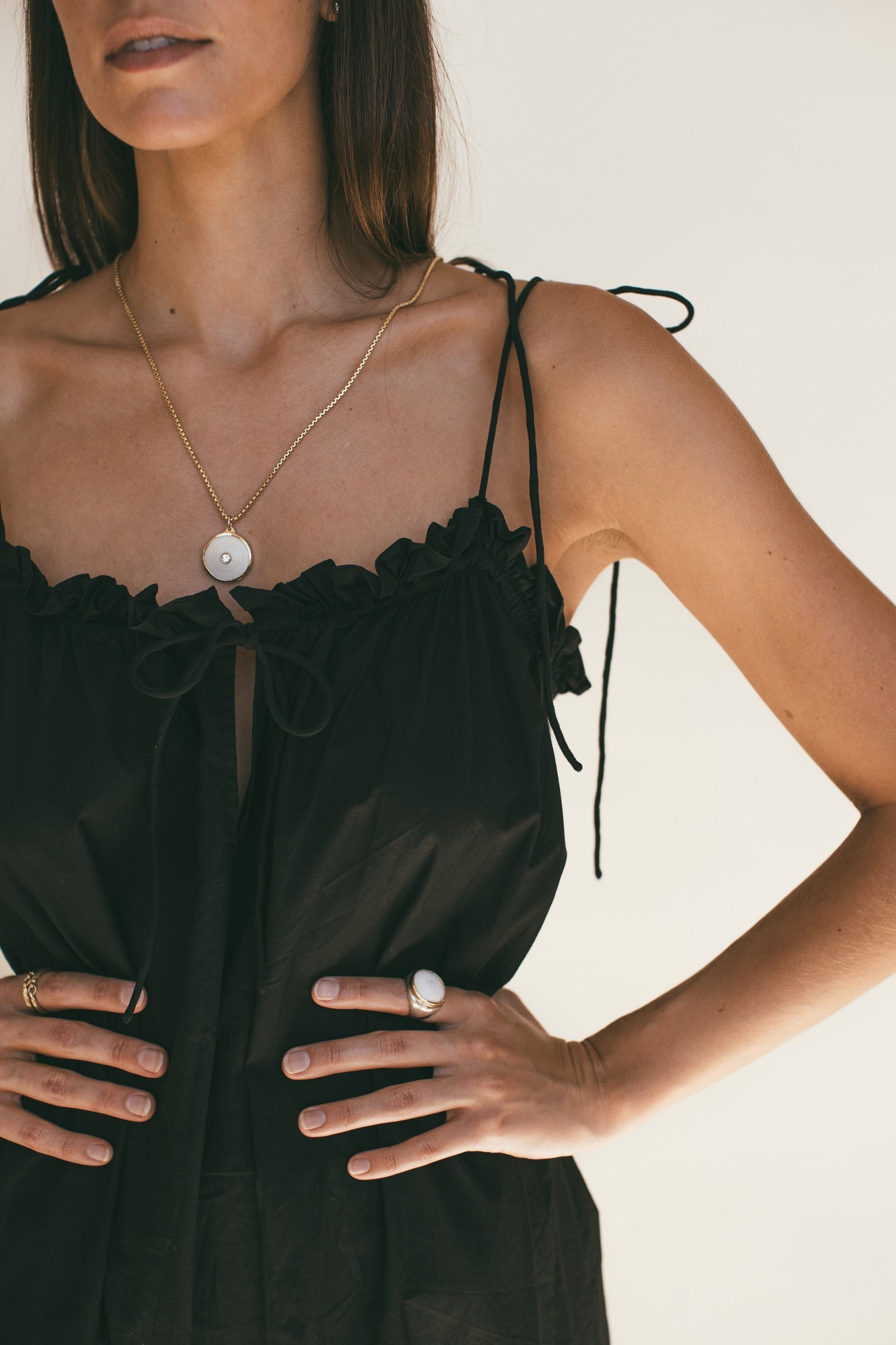 A MODEL WEARING A BLACK DRESS WITH THEMEDIUM 18K GOLD PUKA CHARM WITH DIAMOND-ONE-OF-A-KIND-WHITE