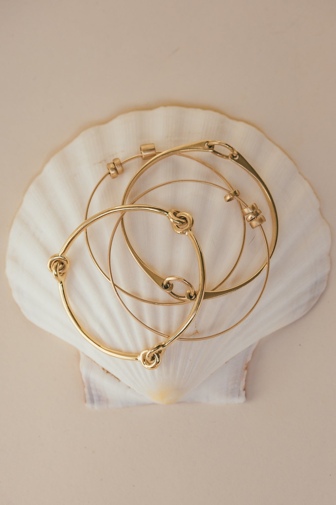 THREE DIFFERENT TYPES OF THE NEST 14K GOLD BRACELET
SITTING ON TOP OF THE SEA SHELLS 