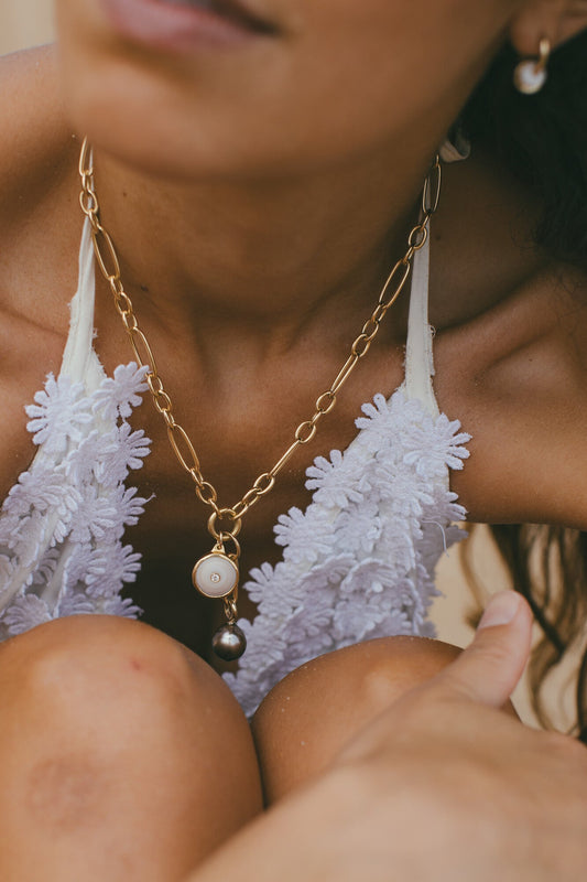 A model wearing SMALL 18K GOLD PUKA CHARM WITH DIAMOND ONE-OF-A-KIND-WHITE