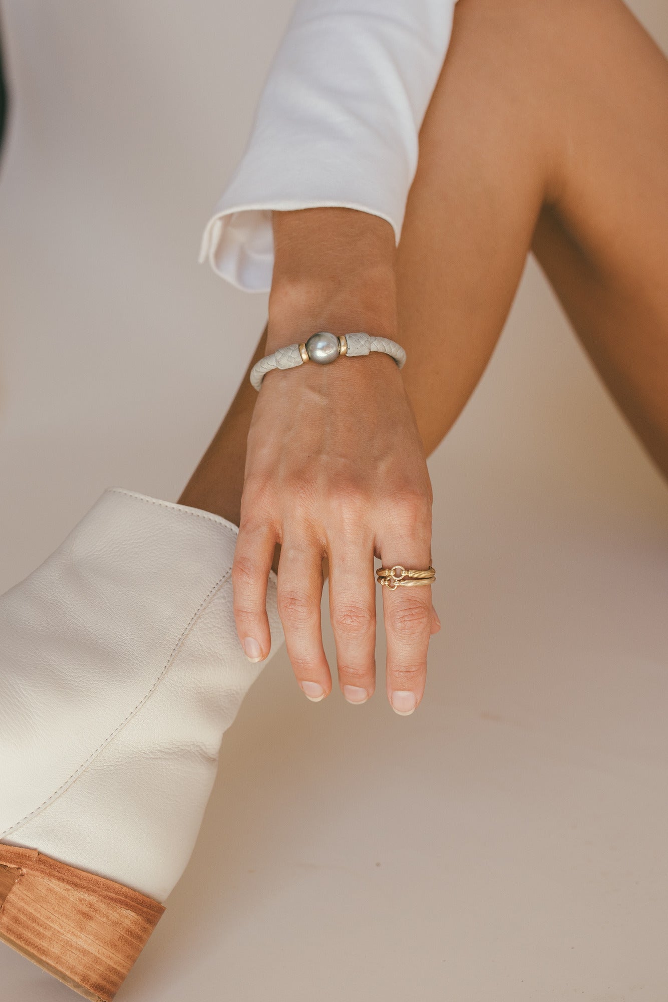 THE TAHA’A 14K GOLD BRACELET WITH TAHITIAN PEARL ON THE MODELS LEFT HAND 