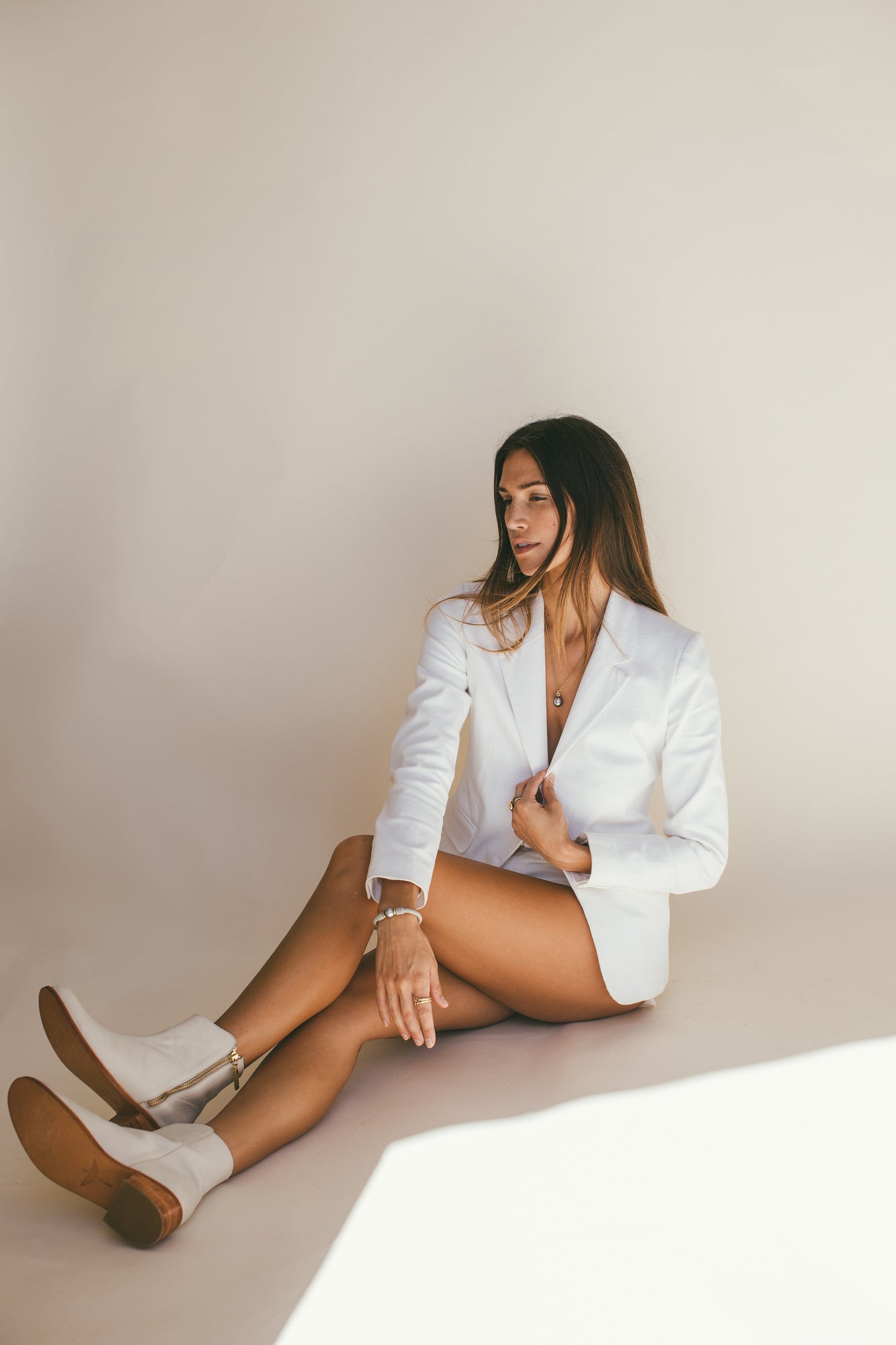 A MODEL WEARING A WHITE BLAZER WITH THE TAHA’A 14K GOLD BRACELET WITH TAHITIAN PEARL ON HER LEFT HAND 