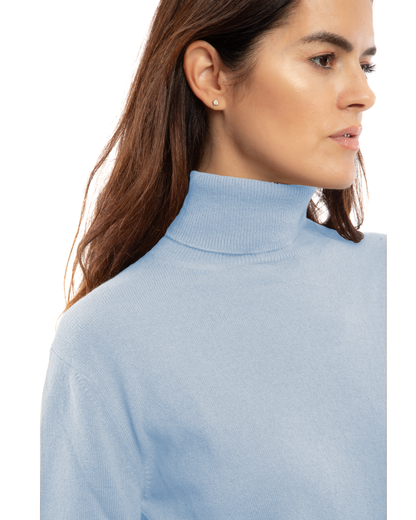 Close-up of the ribbed neckline and fine knit of a Baby Blue cashmere turtleneck sweater on a model.