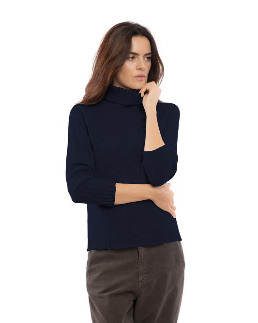 Night Blue classic cashmere turtleneck sweater, front view on a model with one hand at the collar.