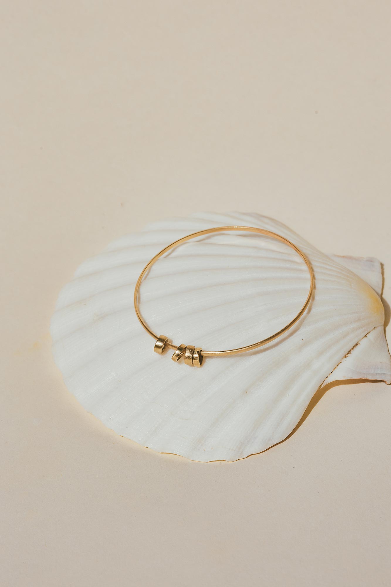 Quatro 14k bangle on sea shell