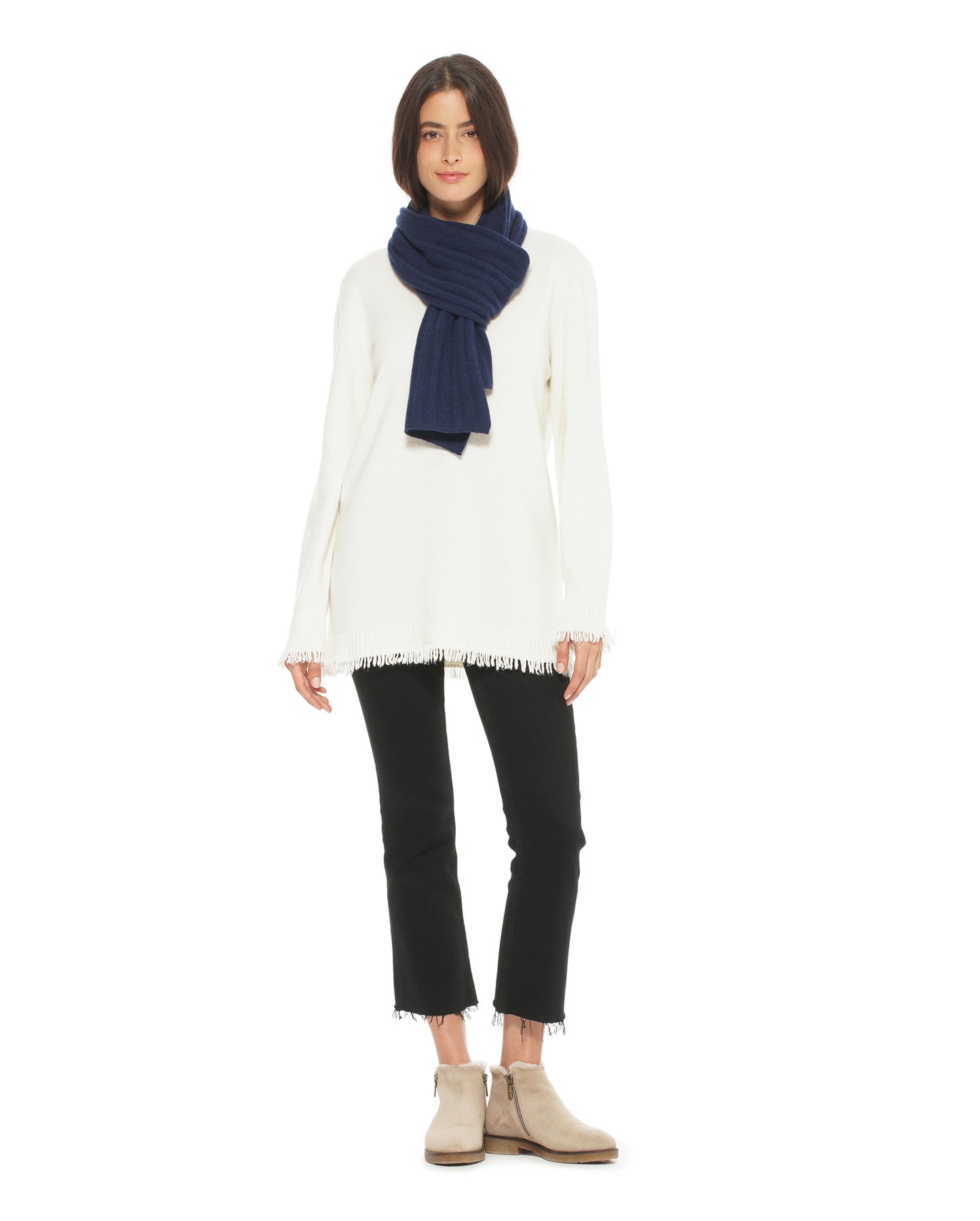 Person wearing a white sweater, black pants, and a navy scarf on a white background