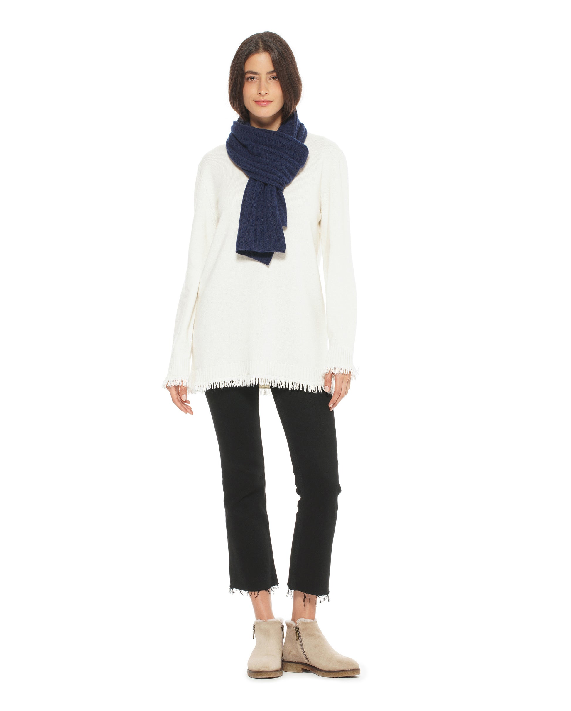 Person wearing a white sweater, black pants, and a navy scarf on a white background
