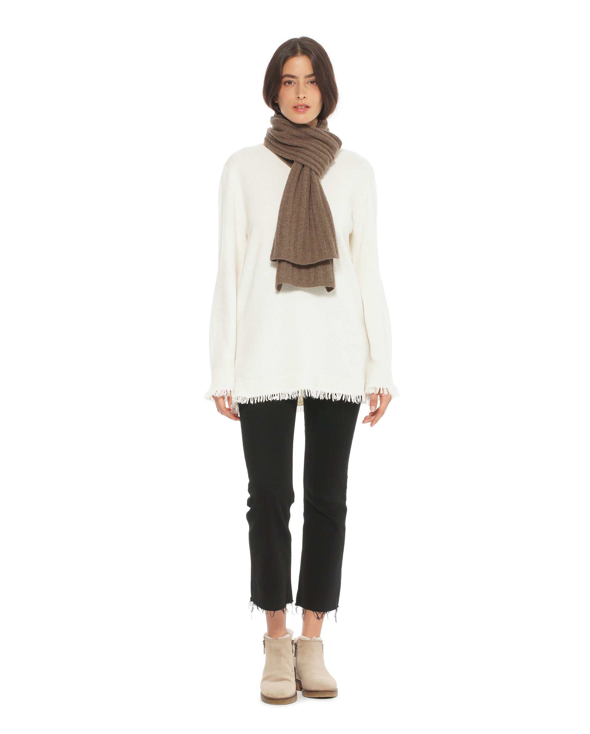 Person wearing a white sweater, black pants, and a brown scarf on a white background